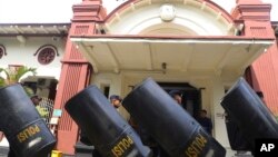 Police carry riot shields in front of a court building in Surabaya, East Java, Indonesia, Jan, 16, 2023, ahead of a trial of five defendants accused of negligence in last October's deadly crowd surge at a soccer match. 