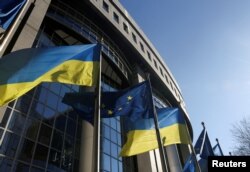 Bendera Uni Eropa dan Ukraina berkibar di luar gedung Parlemen Uni Eropa, di Brussels, Belgia, 28 Februari 2022. (Foto: REUTERS/Yves Herman)