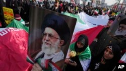 Demonstrators carry an Iranian flag and posters of the Supreme Leader Ayatollah Ali Khamenei during the annual rally commemorating Iran's 1979 Islamic Revolution, in Tehran, Iran, Feb. 11, 2023. 