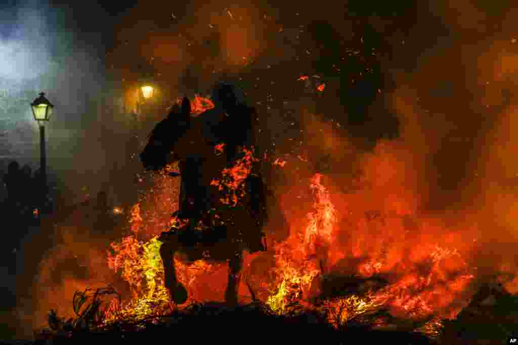 A man rides a horse through a bonfire as part of a ritual in honor of Saint Anthony the Abbot, the patron saint of domestic animals, in San Bartolome de Pinares, Spain, Jan. 16, 2023. (AP Photo/Manu Fernandez)