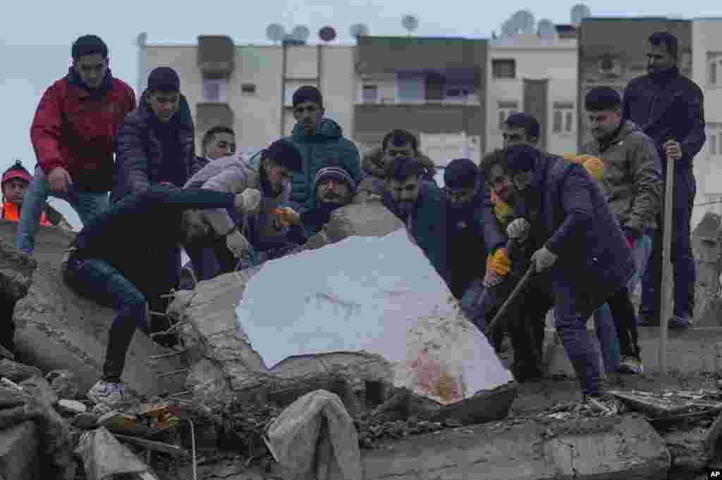 Men search for people among the debris in a destroyed building in Adana, Turkey.&nbsp;A powerful 7.8 magnitude earthquake has rocked wide swaths of Turkey and neighboring Syria, killing more than 2,600 people and injuring thousands more.