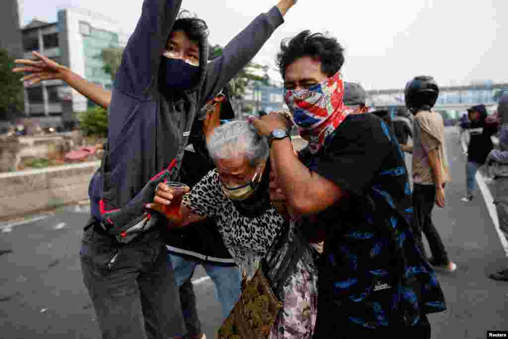 Demonstrators cover an old woman during clashes with police, as they protest against the government&#39;s proposed labor reforms in a controversial &quot;jobs creation&quot; bill in Jakarta, Indonesia.