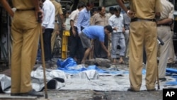 A man moves debris during a clean-up operation near the Opera House, one of the sites of Wednesday's triple explosions, in Mumbai, India, July 15, 2011.