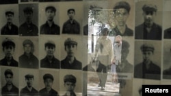 Tourists are reflected on the glass frame of portraits of victims killed in the former Khmer Rouge regime's S-21 security prison, presently known as Tuol Sleng genocide museum, in Phnom Penh, Cambodia. (File)