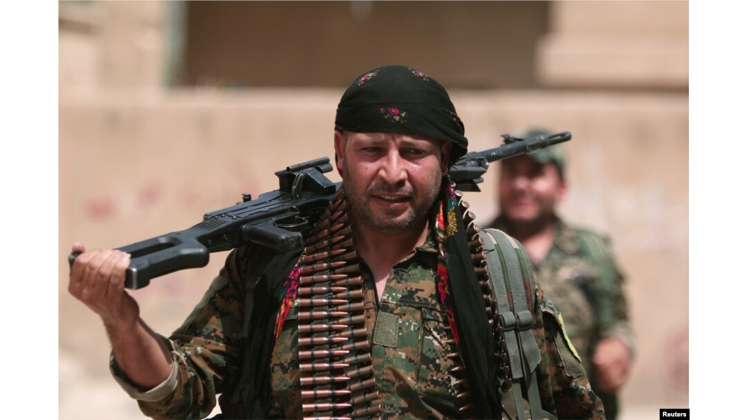 A Kurdish fighter from the People's Protection Units (YPG) carries his weapons as he walks the streets in the northeastern city of Hasaka, Syria, Aug. 21, 2016.