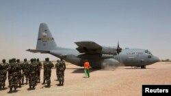 FILE - A C-130 U.S. Air Force plane taxis as Nigerien soldiers stand in formation during a military exercise in Diffa, Niger, March 8, 2014. 