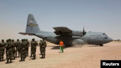 FILE - A C-130 U.S. Air Force plane taxis as Nigerien soldiers stand in formation during the Flintlock 2014 military exercise in Diffa, Niger, March 8, 2014. 
