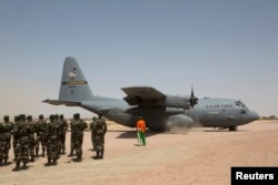 FILE - A C-130 U.S. Air Force plane taxis as Nigerien soldiers stand in formation during the Flintlock 2014 military exercise in Diffa, Niger, March 8, 2014.