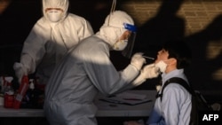 A health worker administers a swab at a temporary COVID-19 novel coronavirus testing center in Bucheon, south of Seoul, May 27, 2020. 