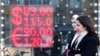 People walk past a currency exchange office screen displaying the exchange rates of US dollars and Euro to Russian rubles in Moscow, Feb. 28, 2022. 