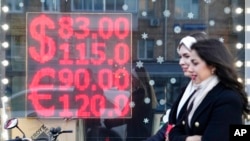 Orang-orang berjalan melewati layar yang menunjukkan nilai tukar mata uang dolar Amerika dan Euro terhadap rubel Rusia di Moskow, pada 28 Februari 2022. (Foto: Ap/Pavel Golovkin)