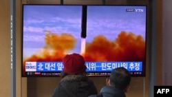 People watch a television screen showing a news broadcast with file footage of a North Korean missile test, at a railway station in Seoul, South Korea, on March 5, 2022.