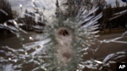A man is seen through a bullet hole of a machine-gunned bus after an ambush in the city of Kyiv, Ukraine, March 4, 2022.