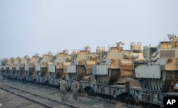 FILE - U.S. servicemen walk by tanks that arrived via train to the U.S. base in Mihail Kogalniceanu, eastern Romania, Feb. 14, 2017. Experts predict that President Trump's proposed $60 billion defense budget hike will face stiff opposition in Congress.