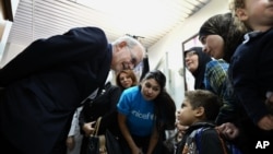 Tổng giám đốc UNICEF Anthony Lake (trái) nói chuyện với một bé trai đến một trung tâm y tế ở Damascus, Syria, để được uống vắc xin ngừa bại liệt, 29/10/13