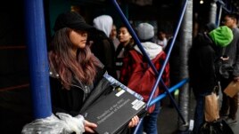 Anna Louisa, 18, receives her school laptop for home study at the Lower East Side Preparatory School, Thursday, March 19, 2020, in New York, as coronavirus restrictions shuttered classrooms throughout the city. (AP Photo/John Minchillo)