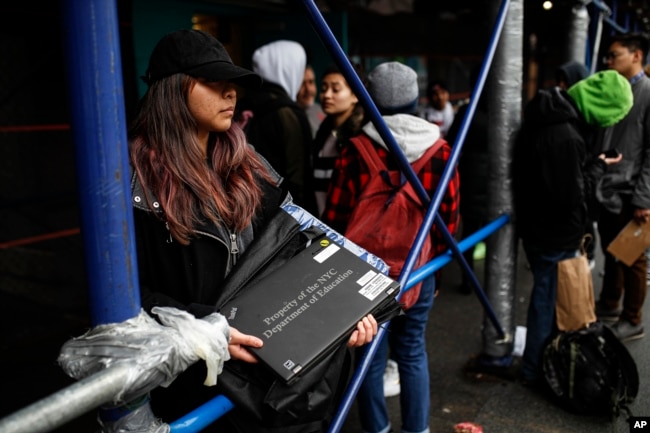 Anna Louisa, 18, receives her school laptop for home study at the Lower East Side Preparatory School, Thursday, March 19, 2020, in New York, as coronavirus restrictions shuttered classrooms throughout the city. (AP Photo/John Minchillo)