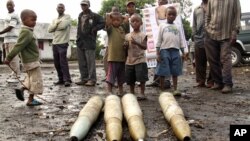 Congolese citizens look at tank shells lying next to roadside, left behind by retreating government troops as they fled assault by M23 rebels, in eastern Congo, Nov. 21, 2012.