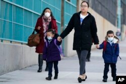 Anak-anak dan pengasuh mereka tiba di sekolah di New York, Senin, 7 Maret 2022. (AP/Seth Wenig)