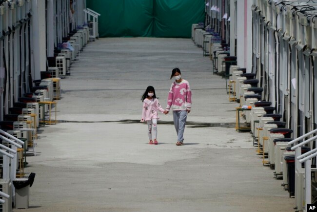 Patients walk along mobile shelters at COVID-19 isolation center in the San Tin area of Hong Kong. People who are believed to be infected with COVID-19 are being held at the center to prevent the spread of the new coronavirus. (AP Photo/Kin Cheung)