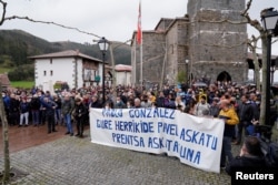 FILE - People stand behind a banner reading "Freedom for our neighbor Pablo Gonzalez. Press Freedom," during a demonstration, after Gonzalez was detained by Polish authorities on espionage charges, in Nabarniz, Spain, March 6, 2022.