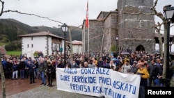 People stand behind a banner reading 'Freedom for our neighbor Pablo Gonzalez. Press Freedom,' during a demonstration, after Gonzalez was detained by Polish authorities on espionage charges, in Nabarniz, Spain, March 6, 2022.