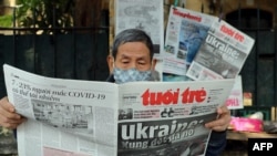 FILE - A man reads a Vietnamese newspaper featuring front-page coverage of the Russian invasion of Ukraine at a stall in Hanoi, Feb. 25, 2022.