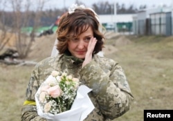 Lesia Ivashchenko, miembro de las Fuerzas de Defensa Territorial de Ucrania, durante su boda con Valerii Fylymonov, en un puesto de control en Kiev, Ucrania, el 6 de marzo de 2022. REUTERS/Mykola Tymchenko.