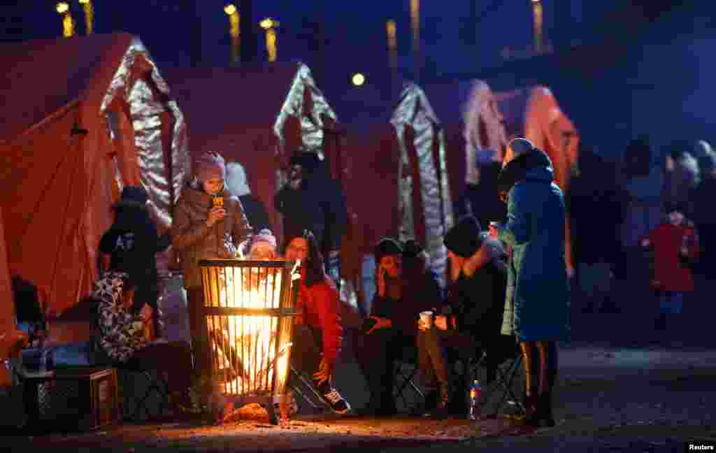 People warm up at a bonfire while waiting to board a train to Krakow after crossing the border from Ukraine to Poland, at the border checkpoint in Medyka, Poland, March 9, 2022.