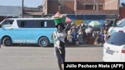 Uma mulher zungueira passa por uma rua em Luanda. 8 de Março, 2022