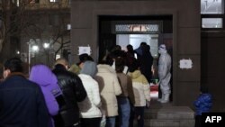 Residents queue to undergo nucleic acid tests for COVID-19 at a residential area in Changchun in China's northeastern Jilin province, March 11, 2022.