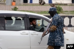 FILE - A Taliban fighter checks a vehicle along a road in Kandahar, Feb. 28, 2022.