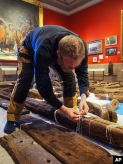 In this Jan. 2018 photo provided by the Pilgrim Hall Museum, Dr. Fred Hocker, Director of Research, Vasa Museum, Stockholm, Sweden, examines Sparrow-hawk timbers at Pilgrim Hall Museum, in Plymouth, Massachussetts.