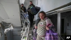 FILE - An injured pregnant woman walks downstairs in a maternity hospital damaged by shelling in Mariupol, Ukraine, March 9, 2022.