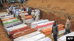 Des civils et des volontaires de la Croix-Rouge assistent le 4 février 2022 à l'enterrement de 62 personnes déplacées qui ont été massacrées dans la nuit du 1er février 2022 dans le camp de déplacés de Plaine Savo, près de Bule, dans la province de l'Ituri.