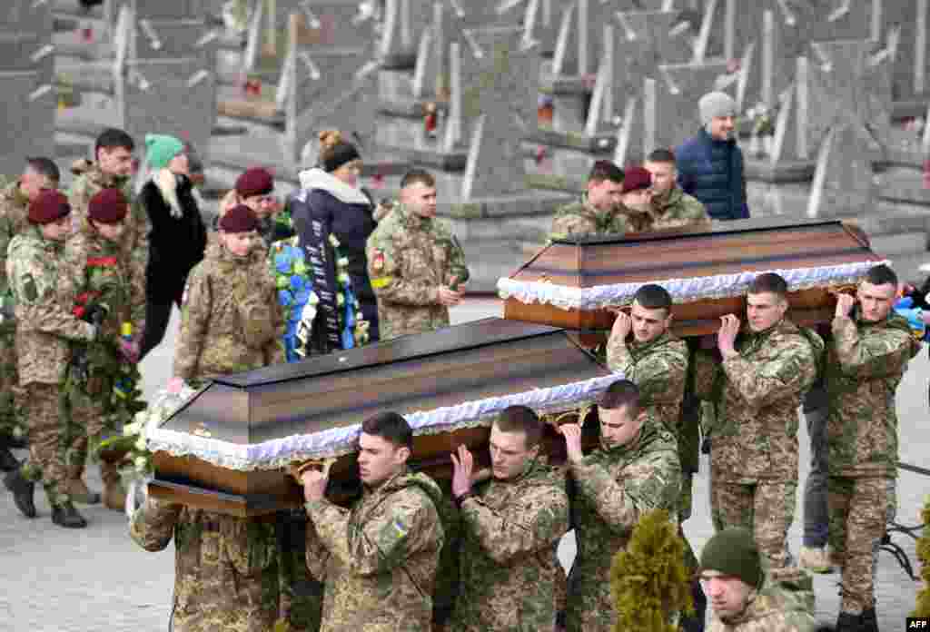 Servicemen carry coffins during funerals of Dmytro Kotenko, Vasyl Vyshyvany and Kyrylo Moroz, Ukrainian servicemen killed during Russia&#39;s invasion of Ukraine, at Lychakiv cemetery in the western city of Lviv, March 9, 2022.