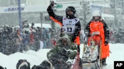 Hanna Lyrek, a musher from Alta, Norway, waves to fans while taking her sled dogs through a snowstorm in downtown Anchorage, Alaska, on Saturday, March 5, 2022, during the ceremonial start of the Iditarod Trail Sled Dog Race.