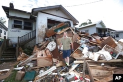 Resident Ken Bridge stands on a pile of his flood-damaged furniture outside his home in Lismore, Australia, March 9, 2022.