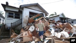 Resident Ken Bridge stands on a pile of his flood-damaged furniture outside his home in Lismore, Australia, March 9, 2022. 