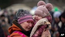 A woman holding a child cries after fleeing from the Ukraine and arriving at the border crossing in Medyka, Poland, March 7, 2022.