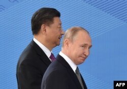 Presiden Rusia Vladimir Putin dan Presiden China Xi Jinping berjalan saat mereka menghadiri pertemuan Dewan Kepala Negara Organisasi Kerja Sama Shanghai (SCO) di Bishkek pada 14 Juni 2019. (Foto: AFP)