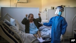 A woman celebrates after learning that she will be dismissed from a hospital in Buenos Aires, Argentina, on Aug. 13, 2020, several weeks after being admitted with COVID-19.