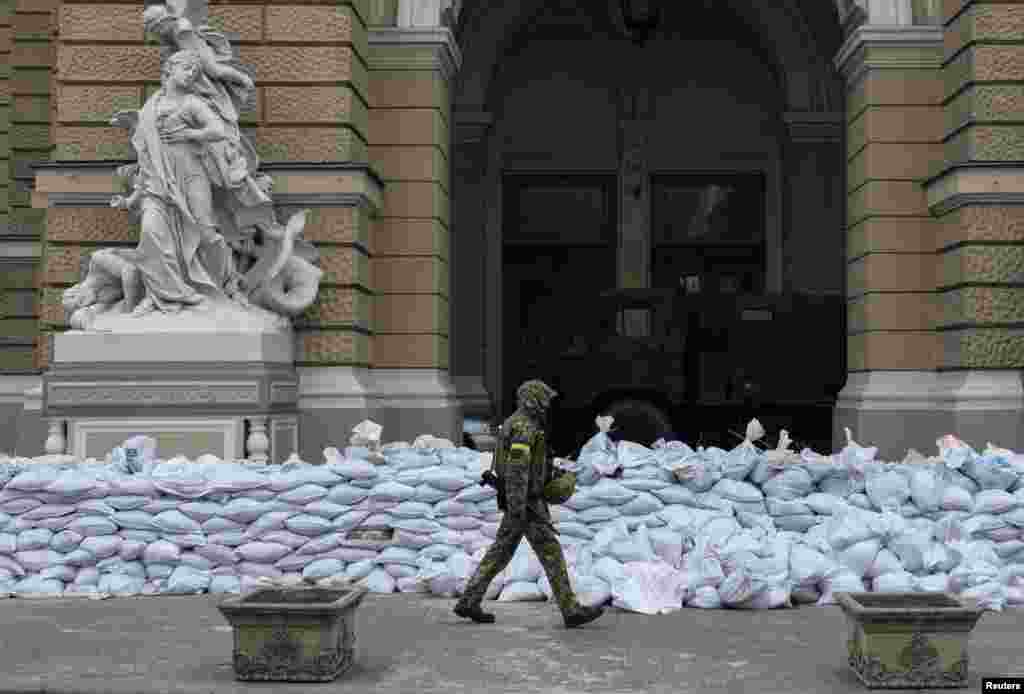 A Ukrainian soldier walks past barricades set outside the entrance of the Odessa National Academic Theatre of Opera and Ballet in Odessa, March 10, 2022.