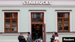 FILE - People wait for their orders outside a Starbucks coffee shop in Moscow, Russia, Oct. 29, 2021.