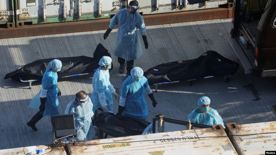 Workers in protective suits move a body to a refrigerated container outside a funeral home, as mortuaries run out of space amid the coronavirus disease (COVID-19) pandemic, in Hong Kong, March 10, 2022. 