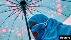 FILE - A woman from China's Uyghur Muslim ethnic group takes part in a demonstration to protest China's treatment of the minority, in Istanbul, Turkey, March 8, 2022.
