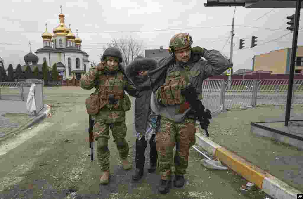 Militares ucranianos ajudam uma senhora idosa, na cidade de Irpin, Ucrânia, 6 de Março, 2022.