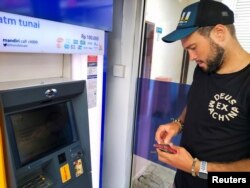 Konstantin Ivanov, warga Rusia (27 tahun) mencoba menarik uang dari rekening bank Rusia-nya di mesin ATM di Kuta, Bali, 8 Maret 2022. (REUTERS/Sultan Anshori)