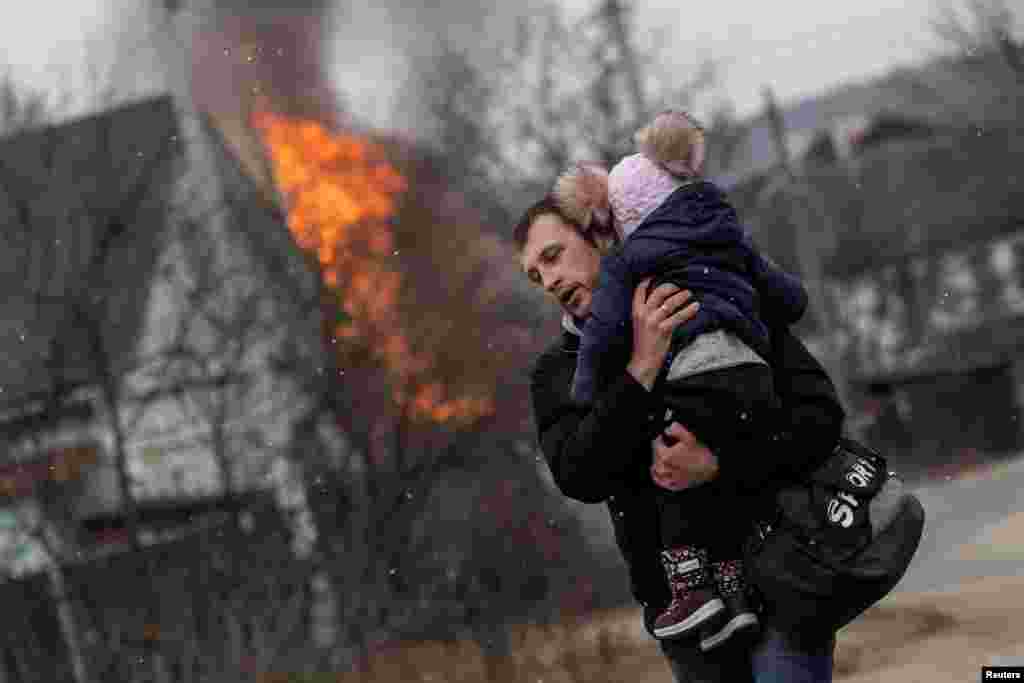 A man and a child escape from the town of Irpin, after heavy shelling on the only escape route used by locals, while Russian troops advance toward the capital of Kyiv, Ukraine, March 6, 2022.