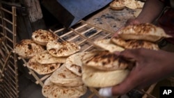 A worker collects Egyptian traditional 'baladi' flatbread, at a bakery, in el-Sharabia, Shubra district, Cairo, Egypt, Wednesday, March 2, 2022. (AP Photo/Nariman El-Mofty)